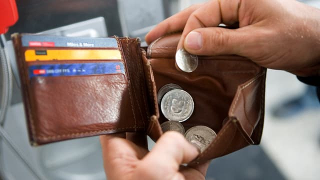 Symbolbild Geld. Person holt Münzen aus einem Portmonee Symbolbild Geld. Person holt Münzen aus einem Portmonee