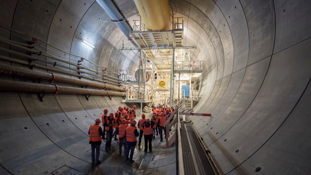 Besucher im Tunnel, im Hintergrund grosse Bohrmaschine Besucher im Tunnel, im Hintergrund grosse Bohrmaschine