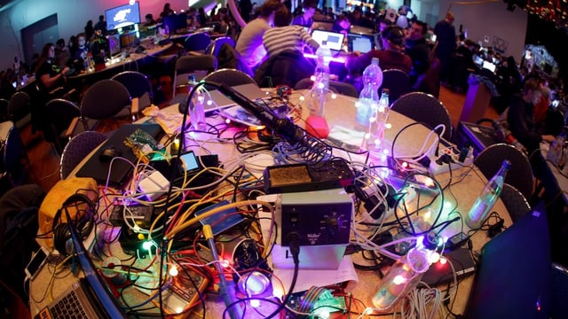 Tisch am CCC-Kongress: Computer und viele Kabel, bunt beleuchtet. Tisch am CCC-Kongress: Computer und viele Kabel, bunt beleuchtet.