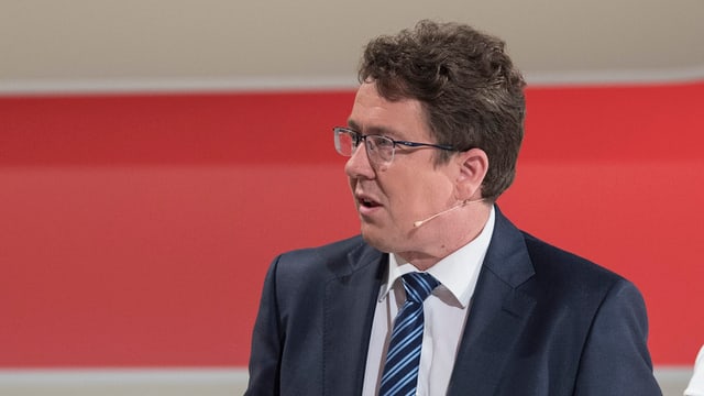 Albert Rösti vor rotem Hintergrund stehend. Albert Rösti vor rotem Hintergrund stehend.