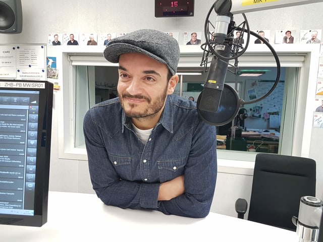 Mann lehnt sich über Sendepult im Radiostudio. Mann lehnt sich über Sendepult im Radiostudio.