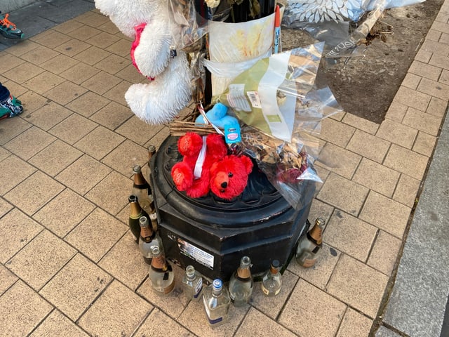 Vor einem Sozialbau die Überreste einer Abdankungsfeier: Bär, Blumen und Alkoholflaschen. Vor einem Sozialbau die Überreste einer Abdankungsfeier: Bär, Blumen und Alkoholflaschen.