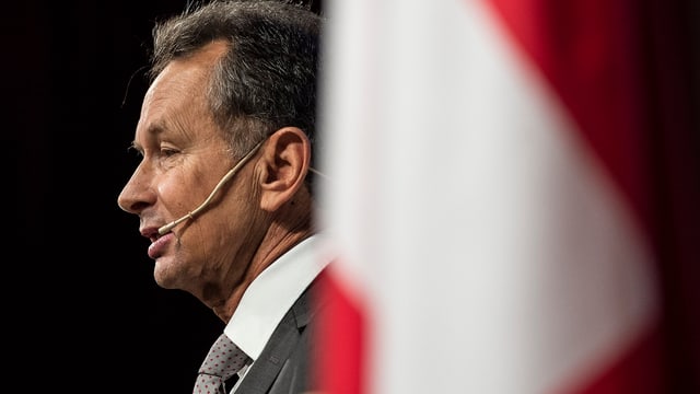 FDP-Parteipräsident Müller von der Seite hinter einer Schweizer Fahne und mit einem Mikrophon an der Backe. FDP-Parteipräsident Müller von der Seite hinter einer Schweizer Fahne und mit einem Mikrophon an der Backe.