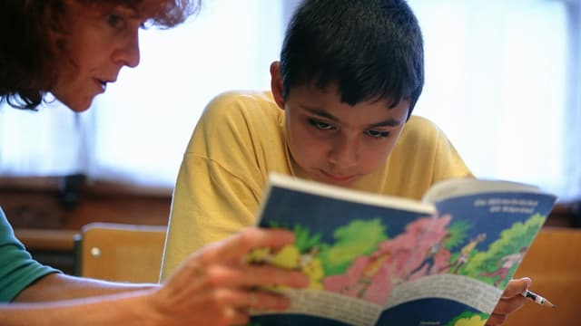Kind mit Lehrerin vor Lehrbuch