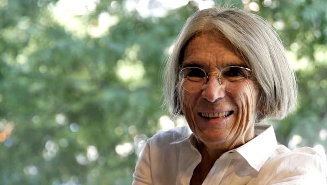 Donna Leon, seitlich auf einem Stuhl sitzend, lachend. Donna Leon, seitlich auf einem Stuhl sitzend, lachend.