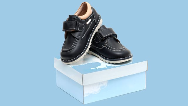 Schwarze Kinderschuhe auf einem Schuhkarton. Schwarze Kinderschuhe auf einem Schuhkarton.