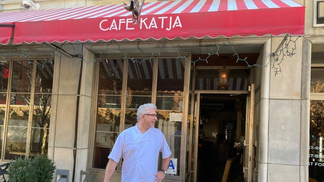 Ein Mann steht vor einem Café und schaut lächelnd nach rechts. Ein Mann steht vor einem Café und schaut lächelnd nach rechts.