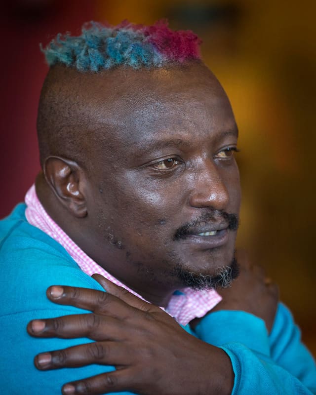 Porträt von der Seite. Binyavanga Wainaina hält die Arme über der Brust gekreuzt und spricht. Porträt von der Seite. Binyavanga Wainaina hält die Arme über der Brust gekreuzt und spricht.