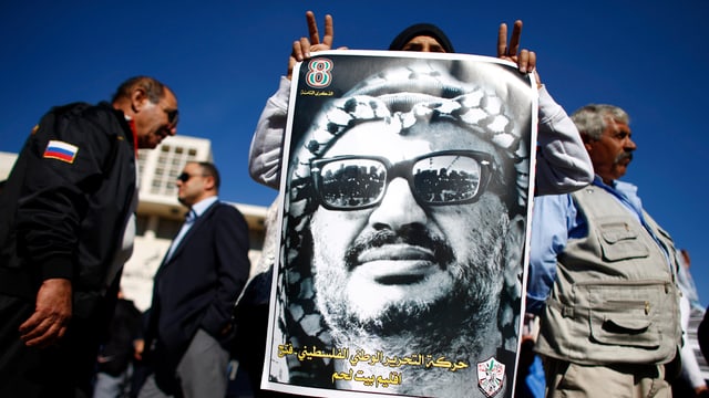 Ein Anhänger von Yassir Arafat hält ein Bild des Palästinänser Führers vor sich hin.