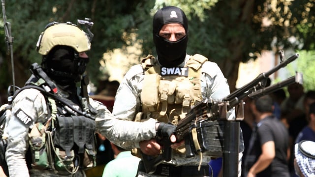 Zwei Swat-Angerhörige in voller Montur inklusive leichtem Maschinengewehr.