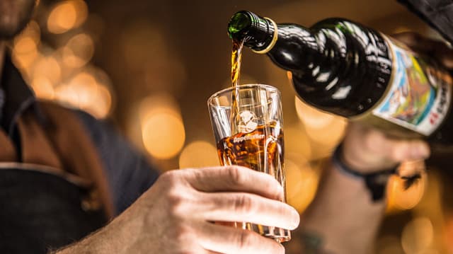 Mann füllt Schnaps in Glas Mann füllt Schnaps in Glas