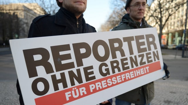 Zwei Männer halten ein Schild von Reporter ohne Grenzen. Zwei Männer halten ein Schild von Reporter ohne Grenzen.