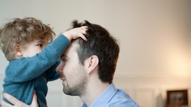 Ein Kind greift seinem Vater mit den Händen in die Haare. Ein Kind greift seinem Vater mit den Händen in die Haare.