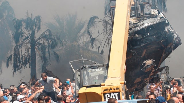 Bagger und zerstörtes Auto vor rauchigem Himmel. Bagger und zerstörtes Auto vor rauchigem Himmel.