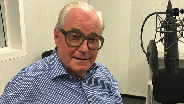Ein Mann mit Hornbrille vor einem Mikrofon in einem Radiostudio. Ein Mann mit Hornbrille vor einem Mikrofon in einem Radiostudio.