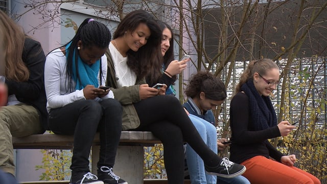 Jugendliche sitzen im Park mit Smartphones Jugendliche sitzen im Park mit Smartphones
