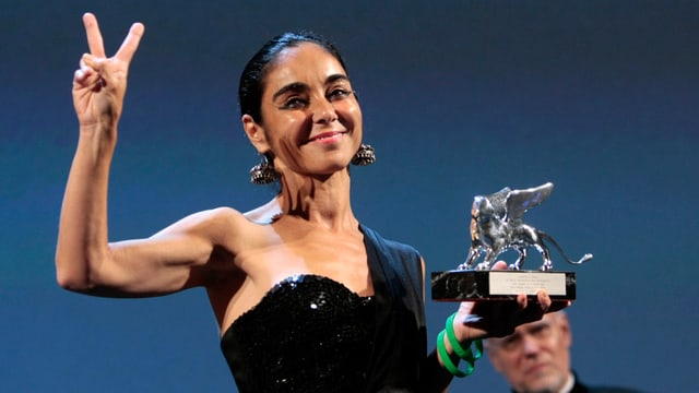 Eine Frau hält stolz eine Trophäe in die Luft. Eine Frau hält stolz eine Trophäe in die Luft.