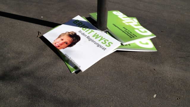 Ein kaputtes Wahlplakat von Brigit Wyss liegt am Boden. Ein kaputtes Wahlplakat von Brigit Wyss liegt am Boden.