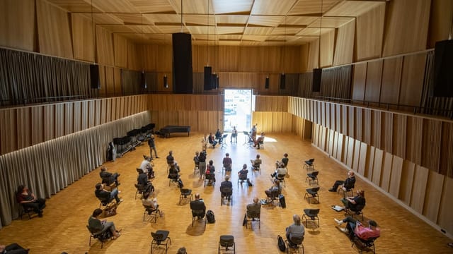Konzertsaal aus dunklem Holz mit Stühlen in der Mitte Konzertsaal aus dunklem Holz mit Stühlen in der Mitte