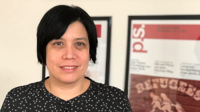 Eine Frau mit schwarzen Haaren steht vor eingerahmten Ausgaben ihrer Zeitung "p.s.". Eine Frau mit schwarzen Haaren steht vor eingerahmten Ausgaben ihrer Zeitung "p.s.".