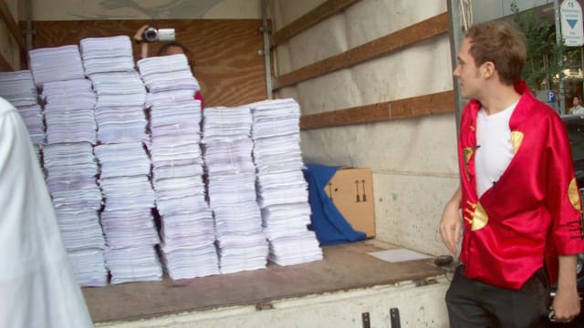 Ein Mann schaut in einen Lastwagen hinein, in dem sich Papierbündel stapeln.
