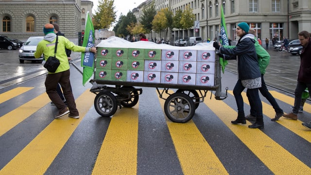 Unterstützer der Initiative «Zersiedelung stoppen» schieben einen Wagen mit Kisten. Unterstützer der Initiative «Zersiedelung stoppen» schieben einen Wagen mit Kisten.