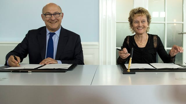 Finanzminister Michel Sapin und Bundesrätin Eveline Widmer-Schlumpf lachen bei der Vertragsunterzeichnung. Finanzminister Michel Sapin und Bundesrätin Eveline Widmer-Schlumpf lachen bei der Vertragsunterzeichnung.