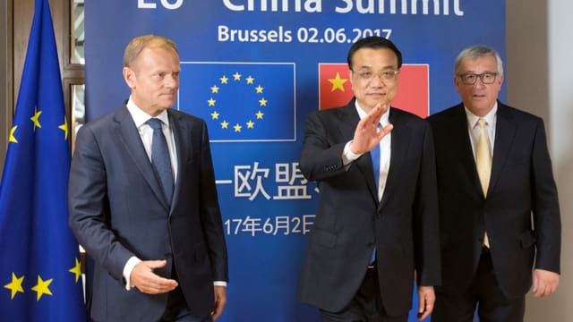 Drei Männer vor einer blauen Wand mit EU- und Chinaflagge. Drei Männer vor einer blauen Wand mit EU- und Chinaflagge.