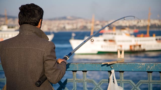Ein Mann angelt alleine in Istanbul.