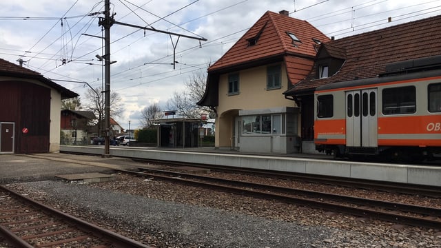 Bahnhofgebäude mit altem, orangem Zug auf einem Abstellgleis. Bahnhofgebäude mit altem, orangem Zug auf einem Abstellgleis.