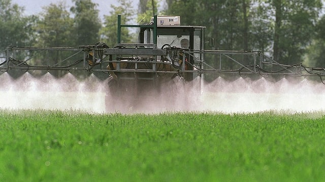 Traktor mit Sprühvorrichtung besprüht Feld mit Pflanzenschutzmitteln Traktor mit Sprühvorrichtung besprüht Feld mit Pflanzenschutzmitteln