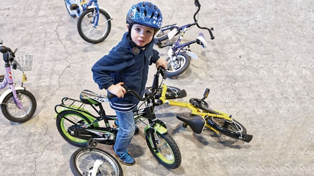 Ein Kind sitzt auf einem Kindervelo, darum herum liegen und stehen andere Kinderfahhräder. Ein Kind sitzt auf einem Kindervelo, darum herum liegen und stehen andere Kinderfahhräder.