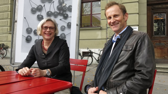 Zwei Personen an einem roten Tisch. Zwei Personen an einem roten Tisch.