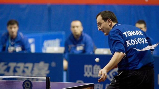 Symbolbild: Kosovarischer Tischtennis-Spieler mit Brille und blauem Shirt mitten in einem Match. Symbolbild: Kosovarischer Tischtennis-Spieler mit Brille und blauem Shirt mitten in einem Match.