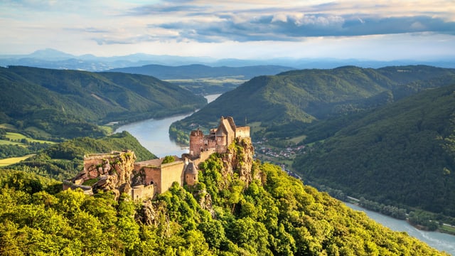 Eine Burgruine auf einem Hügel. Im Hintergrund ist ein Fluss – die Donau – zu sehen. Eine Burgruine auf einem Hügel. Im Hintergrund ist ein Fluss – die Donau – zu sehen.