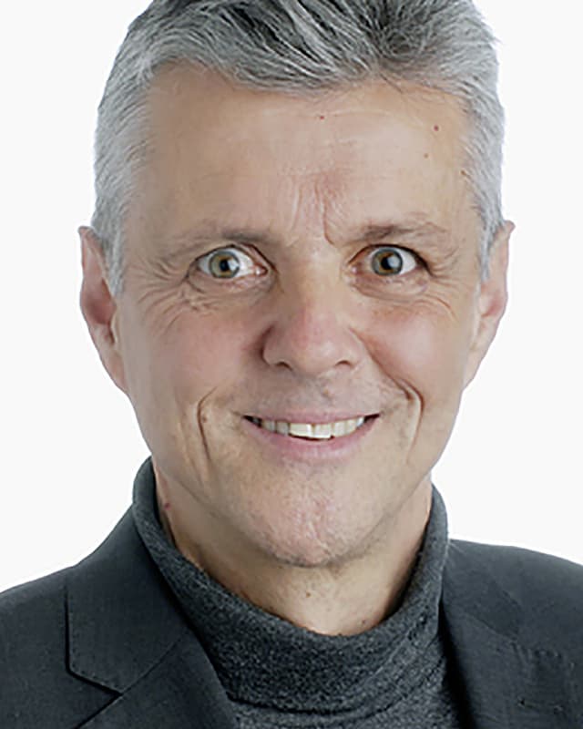 Ein Foto von einem lächelnden Mann mit grauen Haaren und grauem Jackett. Ein Foto von einem lächelnden Mann mit grauen Haaren und grauem Jackett.