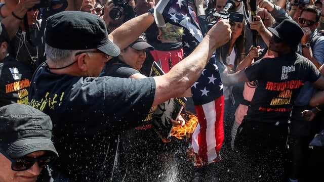 Menschen verbrennen eine US-Flagge. Menschen verbrennen eine US-Flagge.