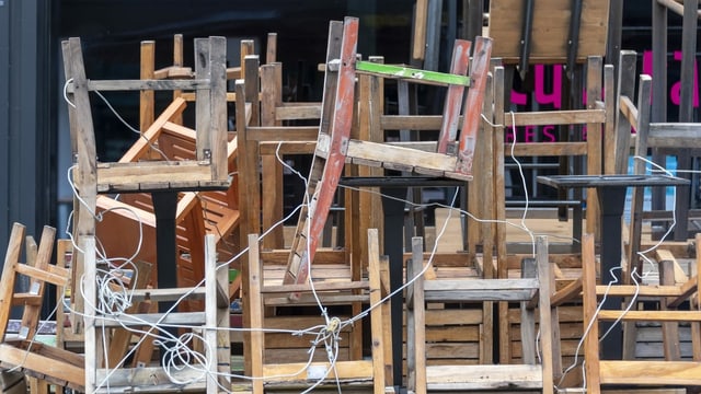 Aufeinandergstapelte und mit Schlössern gesicherte Stühle vor einer Beiz. Aufeinandergstapelte und mit Schlössern gesicherte Stühle vor einer Beiz.