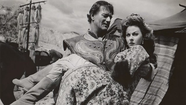 John Wayne trägt Susan Hayward auf Händen.