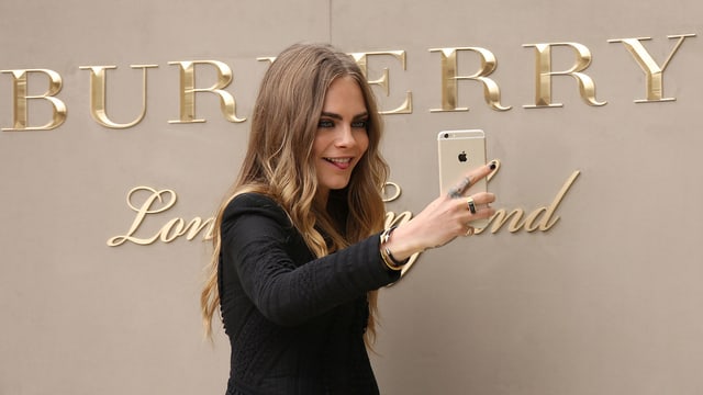 Model fotografiert sich mit dem Handy vor dem «Burberry»-Schriftzug