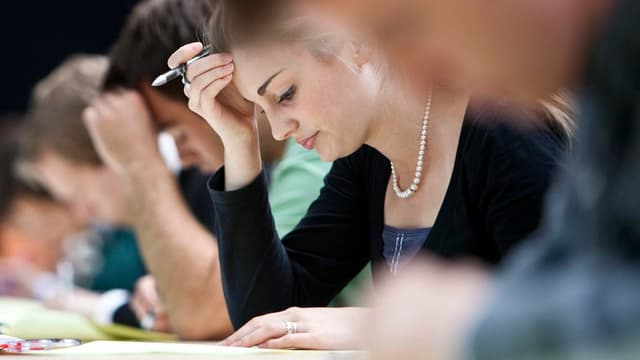 Studierende über Prüfungsaufgaben gebeugt Studierende über Prüfungsaufgaben gebeugt