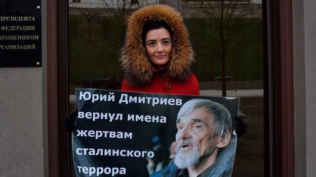 Eine Frau in Wintermantel hält ein Plakat. Eine Frau in Wintermantel hält ein Plakat.
