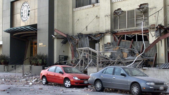 Trümmer an Autos die vor einem Haus stehen. Trümmer an Autos die vor einem Haus stehen.