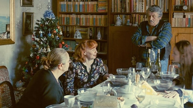 Eine rumänische Familie am Tisch. Die Frauen sitzen, der Vater steht angelehnt an seinem Stuhl. Eine rumänische Familie am Tisch. Die Frauen sitzen, der Vater steht angelehnt an seinem Stuhl.
