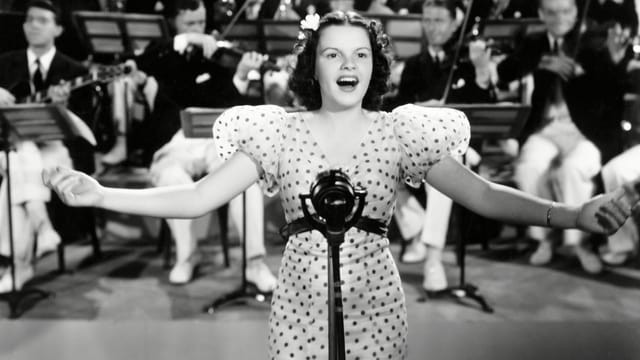Judy Garland singt. Hinter ihr das Orchester. Judy Garland singt. Hinter ihr das Orchester.