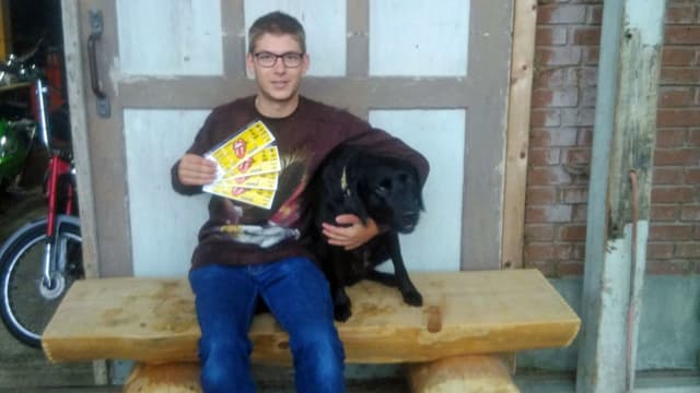 Junger Mann hält seinen Hund und vier Rolling-Stones-Tickets. Junger Mann hält seinen Hund und vier Rolling-Stones-Tickets.
