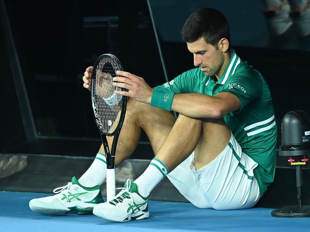 Novak Djokovic sitzt am Boden Novak Djokovic sitzt am Boden