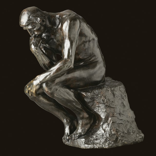 eine Statue, die einen Mensch denkend auf einem Stein sitzend zeigt