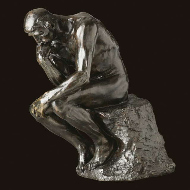eine Statue, die einen Mensch denkend auf einem Stein sitzend zeigt eine Statue, die einen Mensch denkend auf einem Stein sitzend zeigt