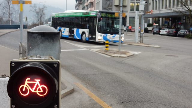 Veloampel zeigt rot - im Hintergrund fährt ein Bus vorbei Veloampel zeigt rot - im Hintergrund fährt ein Bus vorbei